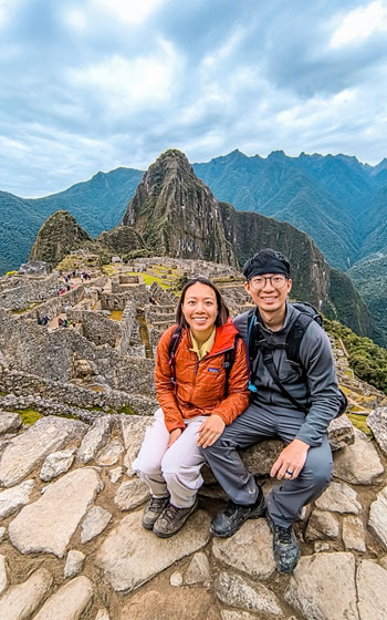 Pareja de turistas explorando la antigua ciudadela de Machu Picchu. Vistas impresionantes e historia inca en el sitio más icónico de Perú.