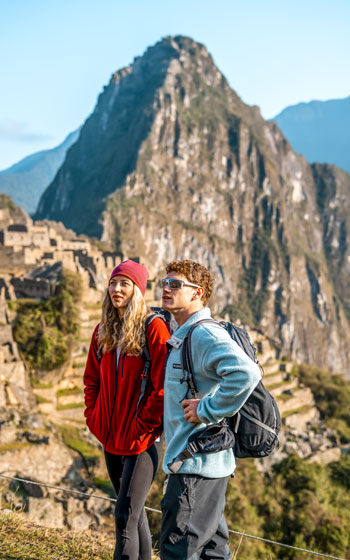 Pareja de turistas posando y disfrutando de la vista de la icónica Ciudadela Inca de Machu Picchu.