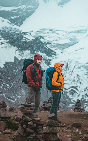 Pareja de turistas haciendo senderismo en la ruta Ausangate de alta montaña. Trekking en los Andes peruanos con vistas espectaculares.