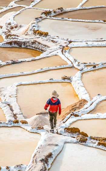 Persona dentro de las Salineras de Maras, explorando las antiguas pozas de sal y el impresionante paisaje andino del Valle Sagrado.