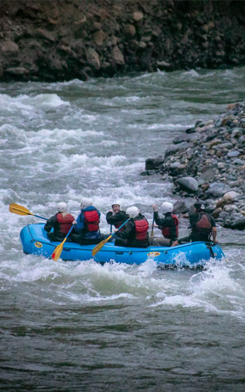 Grupo de turistas haciendo rafting en el río Vilcanota, disfrutando del espectacular paisaje de los Andes peruanos.