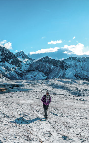 Turista caminando en la nieve en la ruta de trekking hacia la Montaña Arcoíris (Vinicunca), mostrando las desafiantes condiciones andinas.