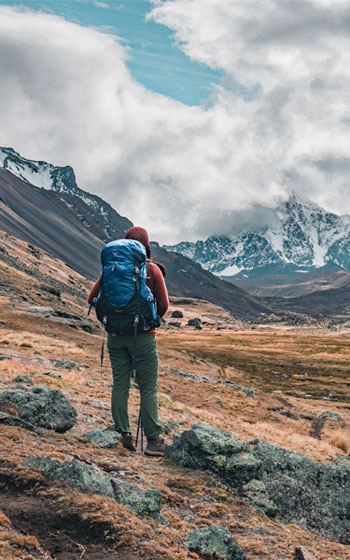 Turista caminando en la ruta de trekking hacia el majestuoso nevado Ausangate, una de las montañas más grandes de los Andes de Perú.