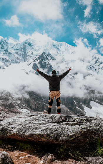 Turista de espaldas, celebrando con las manos en alto frente al majestuoso nevado Salkantay, en la ruta de trekking.