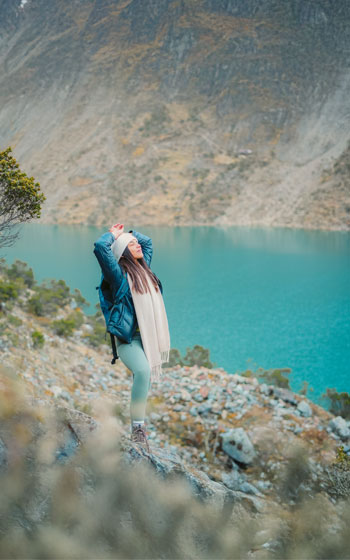Turista disfrutando del paisaje de la famosa Laguna Humantay (color turquesa) en la Ruta Salkantay. Trekking en Cusco y belleza natural andina.