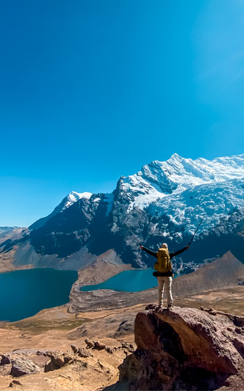 Turista con equipo completo de trekking frente al Nevado Ausangate y sus lagunas turquesas. Aventura y senderismo en la alta montaña andina de Perú.