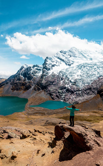Turista posando frente al imponente nevado Ausangate y sus lagunas turquesas, capturando la belleza natural de los Andes de Perú.