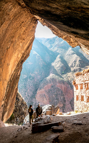 Turista con guía explorando el sitio arqueológico Ñaupa Iglesia en la Ruta de la Cantera Inca. Historia antigua de los Andes peruanos.