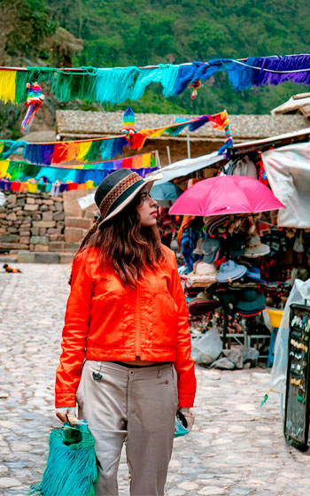Turista explorando el vibrante y colorido mercado artesanal de Pisac, un punto clave en el Valle Sagrado de los Incas.