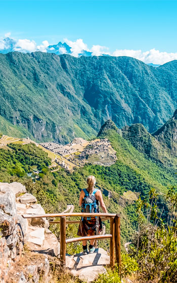 Turista observando la icónica vista panorámica de la majestuosa ciudadela Inca de Machu Picchu desde un punto alto.