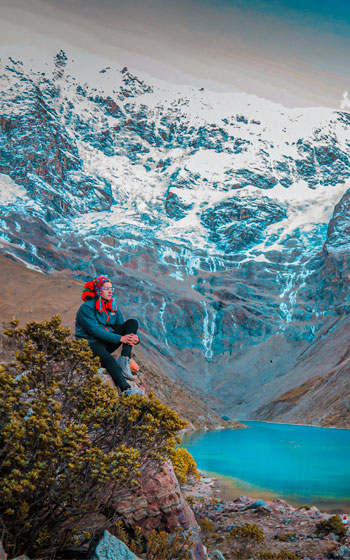 Turista sentado frente a la impresionante Laguna Humantay y su nevado, en la ruta de trekking Salkantay.