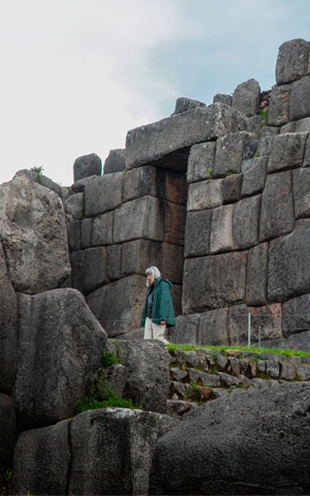 Turista visitando las grandes murallas de piedra del sitio arqueológico de Sacsayhuaman, la imponente fortaleza inca de Cusco.