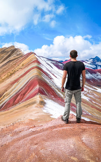 Turista observando la magnífica Montaña Arcoíris (Vinicunca), famosa por sus siete colores en la cordillera del Cusco.