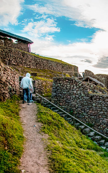 Turista visitando el sitio arqueológico de Pisac, admirando sus terrazas incas, construcciones ancestrales y las impresionantes vistas del Valle Sagrado.