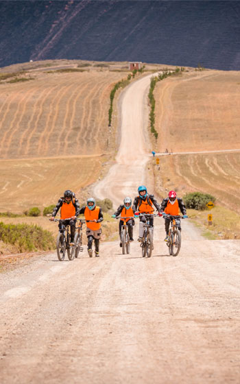 Turistas en bicicleta a lo largo de la ruta escénica Maras Moray, con vistas a las impresionantes terrazas agrícolas incas de Perú.