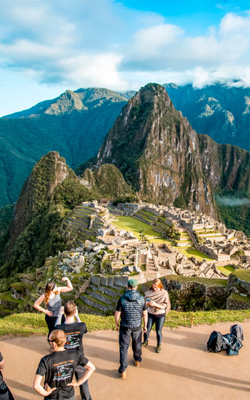 Grupo de turistas admirando el maravilloso paisaje que rodea la histórica Ciudadela Inca de Machu Picchu.