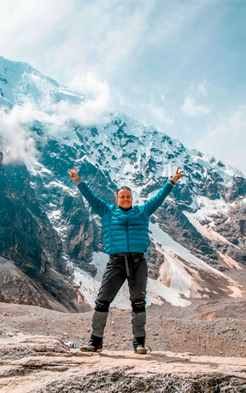 Grupo de turistas con equipo completo de trekking celebrando con las manos en alto en el Paso Salkantay, el punto más alto del Salkantay Trek.