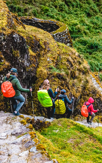 Grupo de turistas descendiendo los escalones de piedra del Camino Inca, en la ruta hacia Machu Picchu.
