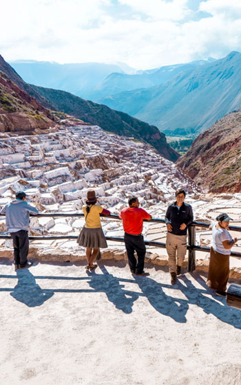 Grupo de visitantes explorando las famosas Salineras de Maras, admirando los pozos de sal y el paisaje andino del Valle Sagrado de Perú.