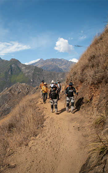 Grupo de turistas y su guía en el sendero de trekking hacia el sitio arqueológico de Choquequirao, en los impresionantes Andes peruanos.