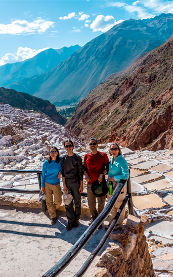 Grupo de turistas visitando las famosas Salineras de Maras, admirando las deslumbrantes terrazas de sal y el paisaje del Valle Sagrado de Perú.