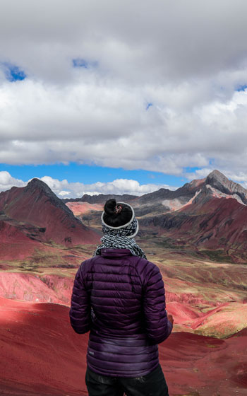 Turistas contemplando el impresionante Valle Rojo en la ruta hacia la Montaña de Colores (Vinicunca), admirando el singular paisaje geológico de Perú.