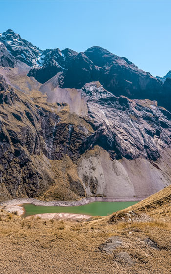 Vista panorámica de la laguna Ancascocha con una imponente montaña al fondo, destacando la impresionante belleza natural de los Andes peruanos.