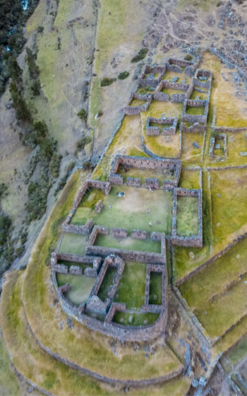 Vista panorámica del sitio arqueológico de Racaypata, mostrando sus antiguas ruinas incas enmarcadas por el impresionante paisaje montañoso de los Andes peruanos.
