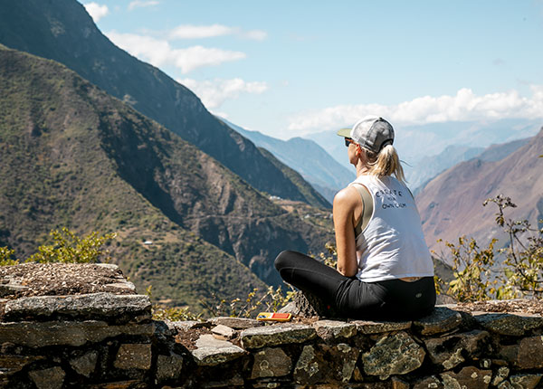 Turista caminando por la ruta hacia Choquequirao, rodeado de las imponentes montañas andinas y la belleza natural intacta de los paisajes sagrados del Perú.