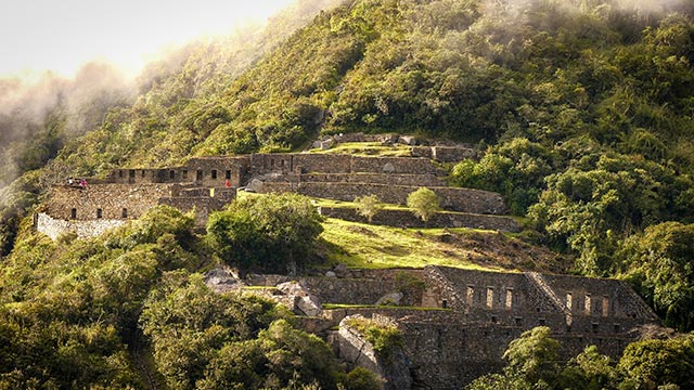 Magníficas construcciones de las ruinas de Choquequirao situadas en medio de imponentes montañas andinas, mostrando la arquitectura inca y la majestuosidad del paisaje peruano.