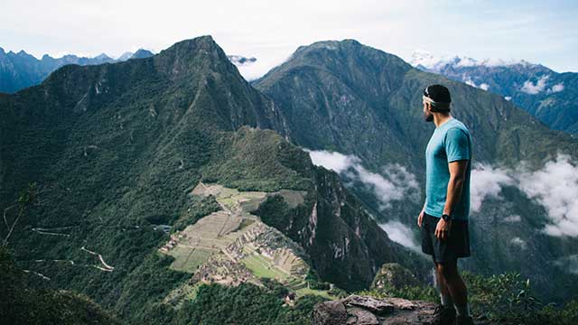 Vista de la maravilla del mundo, Machu Picchu, rodeada de neblina y exuberante vegetación, destacando la majestuosidad de la ciudadela inca y los paisajes andinos del Perú..