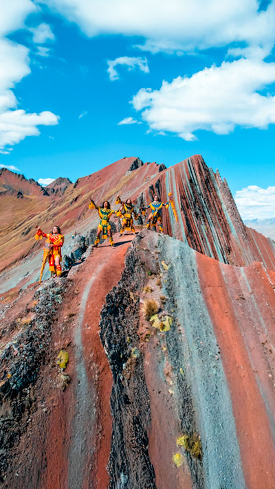 Grupo de personas disfrutando de la montaña Pallay Punchu en Layo, rodeados de impresionantes paisajes andinos y vibrantes colores naturales.