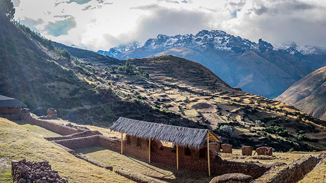 Impresionante vista del Sitio Arqueológico Pre-Inca de Huchuy Qosqo y sus terrazas, ubicado en medio de majestuosas montañas andinas, destacando la arquitectura ancestral y los paisajes peruanos.