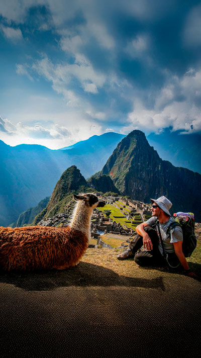 Preciosa foto del encuentro de los habitantes naturales de Machu Picchu con un visitante, una llama y su huésped en el Santuario Inca.