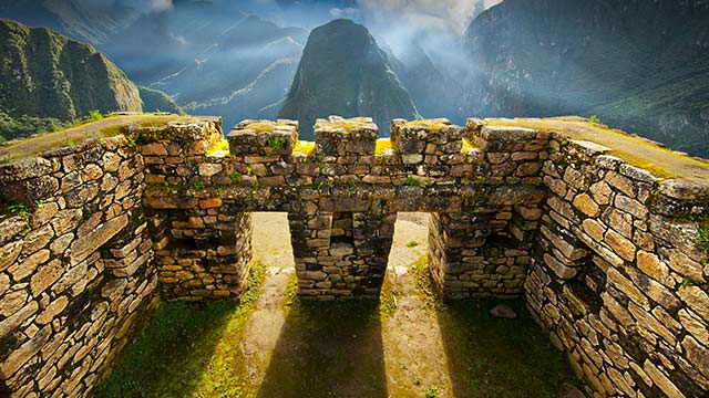 Arquitectura y construcciones incas de Machu Picchu con la majestuosa montaña Putucusi de fondo, mostrando la ingeniería ancestral y los impresionantes paisajes de los Andes peruanos.