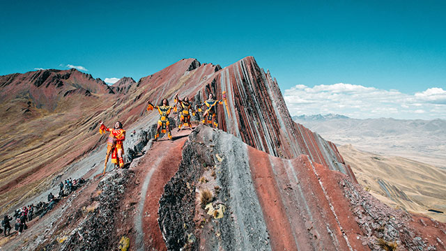 Grupo de personas disfrutando de la montaña Pallay Punchu en Layo, rodeados de impresionantes paisajes andinos y vibrantes colores naturales.