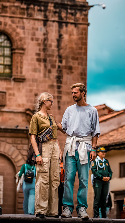Pareja de turistas en la Plaza de Armas del Cusco, la plaza principal de la ciudad, disfrutando de su arquitectura colonial e historia.