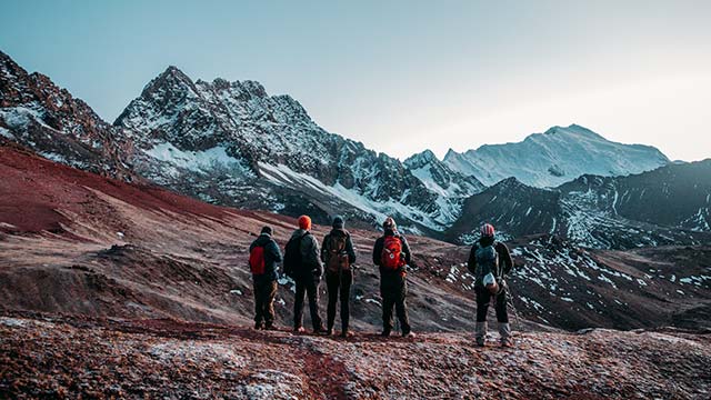 Turista feliz disfrutando del impresionante paisaje del Valle Rojo durante la caminata de 2 días a la Montaña de Colores y Valle Rojo, rodeado de vibrantes paisajes altoandinos en Perú.