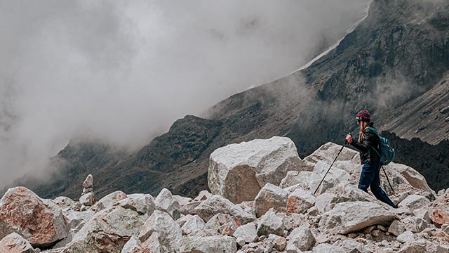 Turista levantando las manos en el paso de Salkantay, rodeado de las imponentes montañas de Cusco durante la expedición a la Laguna Humantay y Salkantay.