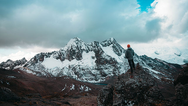 Turista contemplando la magnífica vista del Glaciar Tacusiri en la ruta del Ausangate, rodeado de impresionantes paisajes altoandinos en Perú.