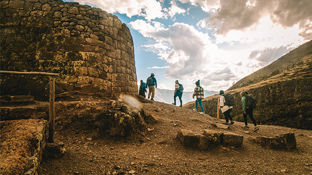 Turistas en el increíble sitio arqueológico de Ollantaytambo, disfrutando la vista panorámica del pueblo y sus majestuosas construcciones incas.