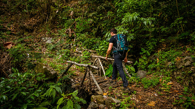 Turista disfrutando de la tirolesa en la ruta Inca Jungle hacia Machu Picchu, rodeado de exuberantes paisajes andinos y bosques tropicales del Perú.