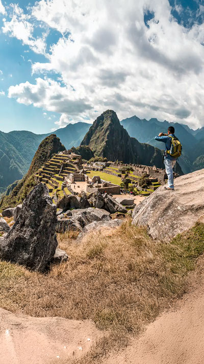 Turista tomando una foto del maravilloso sitio arqueológico de Machu Picchu en Perú, capturando su majestuosidad y belleza histórica.