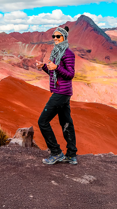 Turista feliz disfrutando del impresionante paisaje del Valle Rojo durante la caminata de 2 días a la Montaña de Colores y Valle Rojo, rodeado de vibrantes paisajes altoandinos en Perú.
