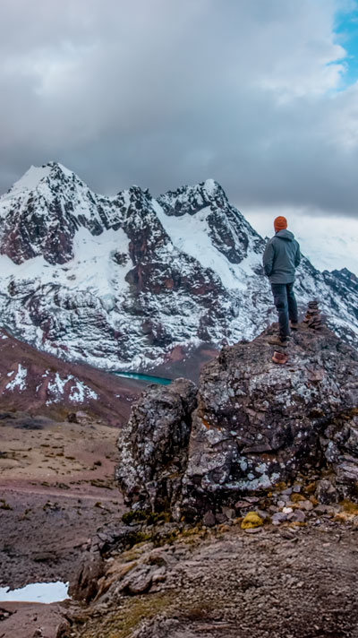 Turista contemplando la magnífica vista del Glaciar Tacusiri en la ruta del Ausangate, rodeado de impresionantes paisajes altoandinos en Perú.