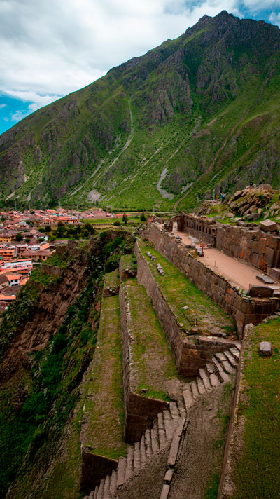 Turistas en el increíble sitio arqueológico de Ollantaytambo, disfrutando la vista panorámica del pueblo y sus majestuosas construcciones incas.