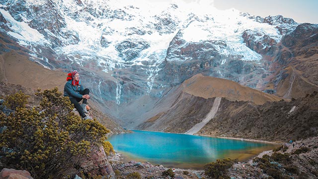 Vista panorámica de turistas admirando la asombrosa Laguna Humantay bajo la imponente Montaña Humantay, rodeada de paisajes andinos.