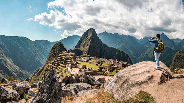 Turista tomando una foto del maravilloso sitio arqueológico de Machu Picchu en Perú, capturando su majestuosidad y belleza histórica.