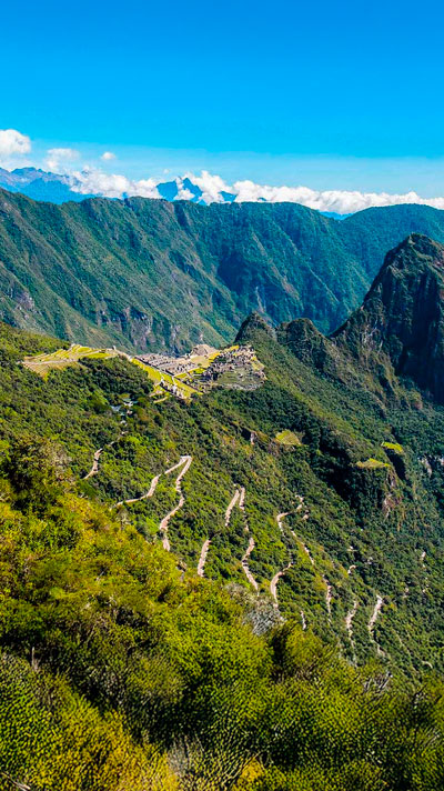 Vista panorámica del Santuario de Machu Picchu desde la Puerta del Sol (Inti Punku), mostrando la majestuosidad de la ciudadela inca y los impresionantes paisajes andinos que la rodean.