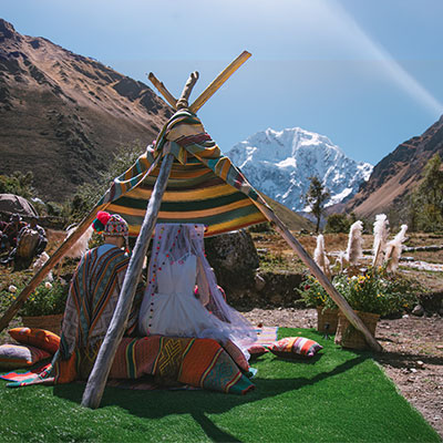 Pareja vestida con prendas tradicionales participando en una ceremonia de boda andina oficiada por un chamán frente a los nevados Salkantay y Humantay.